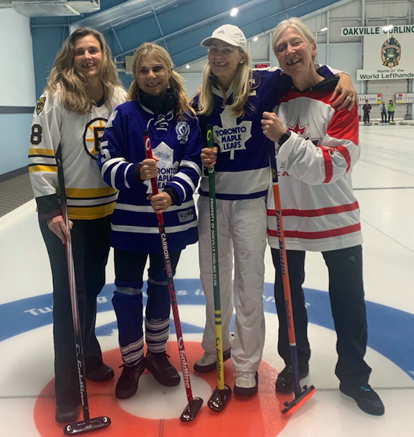 A group of people standing together with hockey sticksDescription automatically generated